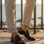 Bugatti Mansueto Bordo premium leather comfort slip-ons with a dark brown finish, styled with beige trousers.
