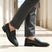 bugatti Mansueto Flex Revo penny loafers in dark green premium leather worn with grey dress pants.
