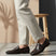 bugatti Tryst dark brown premium leather loafers with a classic penny strap, worn with beige pants.