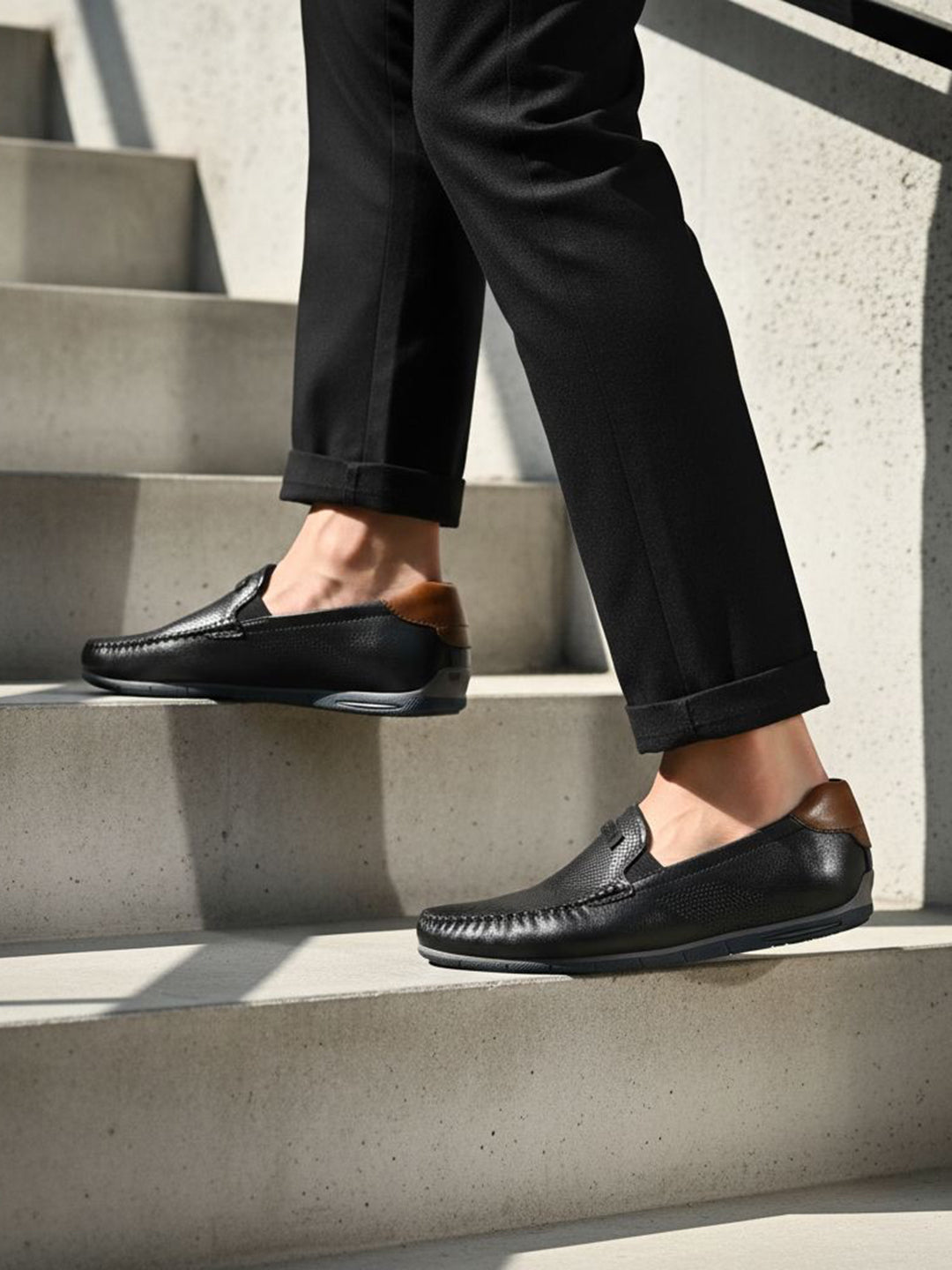 bugatti Chesley dark blue leather slip-on shoe with brown accent on a person walking on stairs.