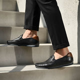 bugatti Chesley dark blue leather slip-on shoe with brown accent on a person walking on stairs.