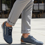 Lifestyle shot of bugatti Trevor blue Comfort Sneakers, a perforated leather shoe with brown heel detail, worn with gray slacks.
