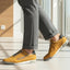 Lifestyle shot of bugatti Trevor yellow comfort sneakers, with grey laces, a perforated pattern, and grey dress pants.
