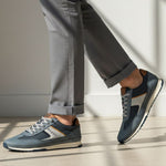 Lifestyle shot of bugatti Riptide blue comfort sneakers paired with gray dress pants and a cuffed hem.