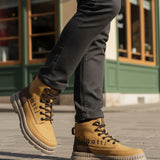 Lifestyle shot of bugatti Pallario beige comfort casual boots with dark brown accents, worn with grey pants.
