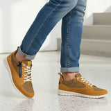 Lifestyle shot of bugatti Palenque yellow leather sneakers with white soles, worn with blue jeans.
