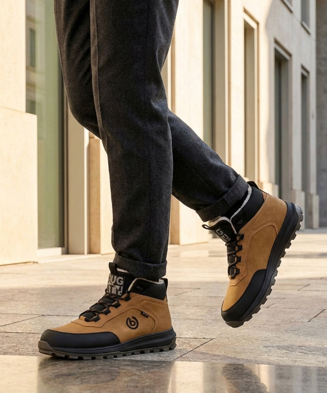 Lifestyle view of bugatti Columb Cognac Comfort Sneakers, with dark trousers and light-colored building in the background.