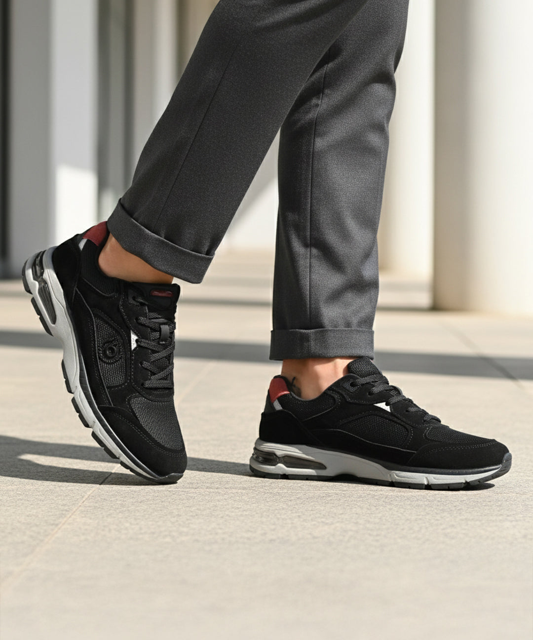 bugatti Parry black premium leather sneakers shown on a model wearing gray dress pants.
