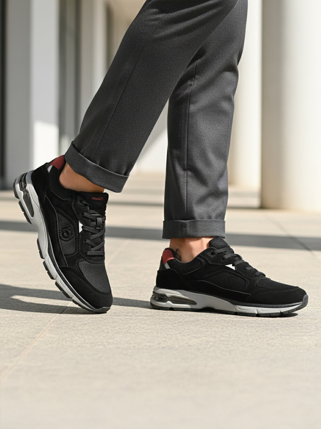 bugatti Parry black premium leather sneakers shown on a model wearing gray dress pants.
