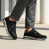 bugatti Parry black premium leather sneakers shown on a model wearing gray dress pants.

