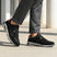 bugatti Parry black premium leather sneakers shown on a model wearing gray dress pants.
