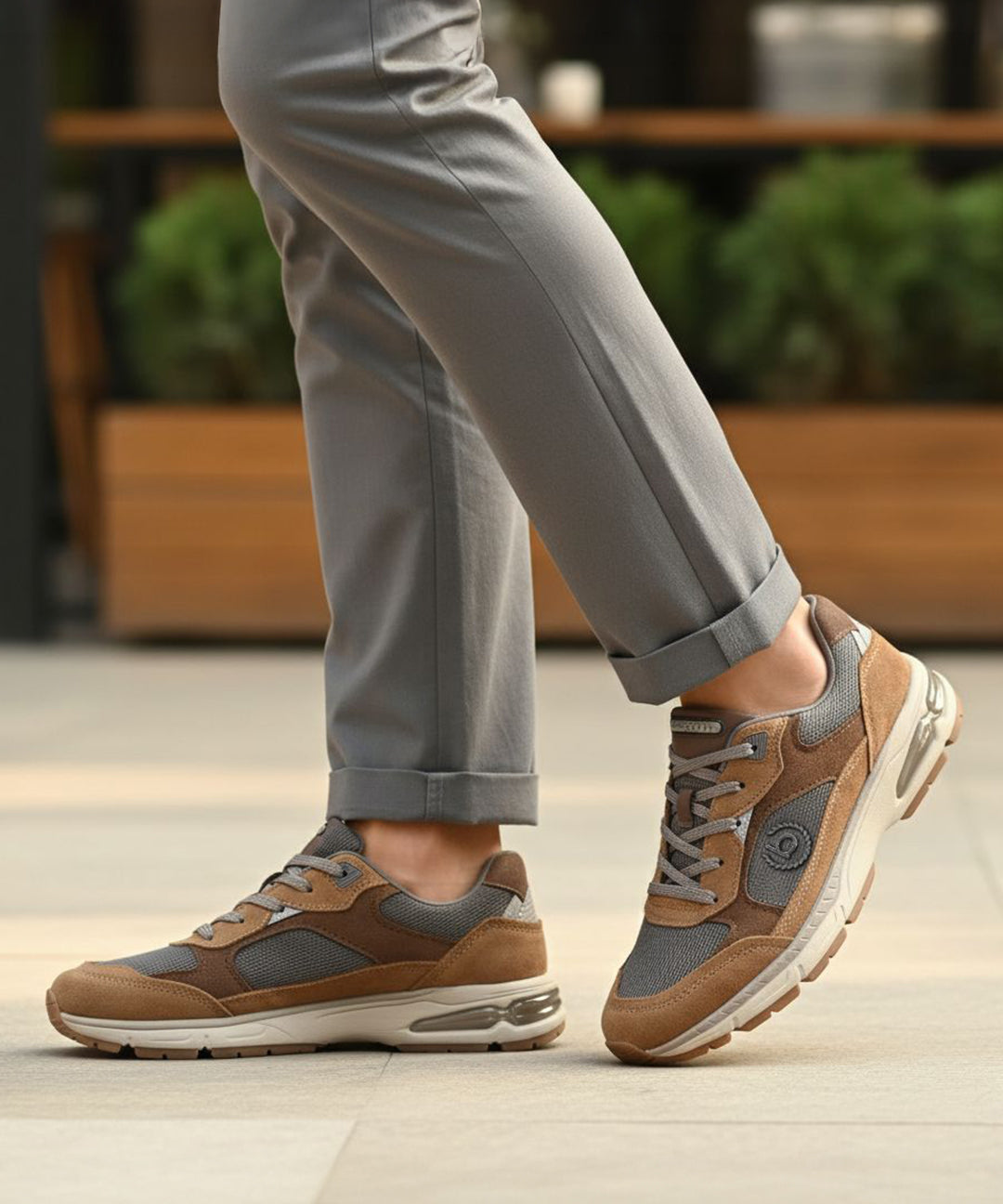 bugatti Parry cognac leather athleisure sneakers with gray mesh detail, worn with gray pants.