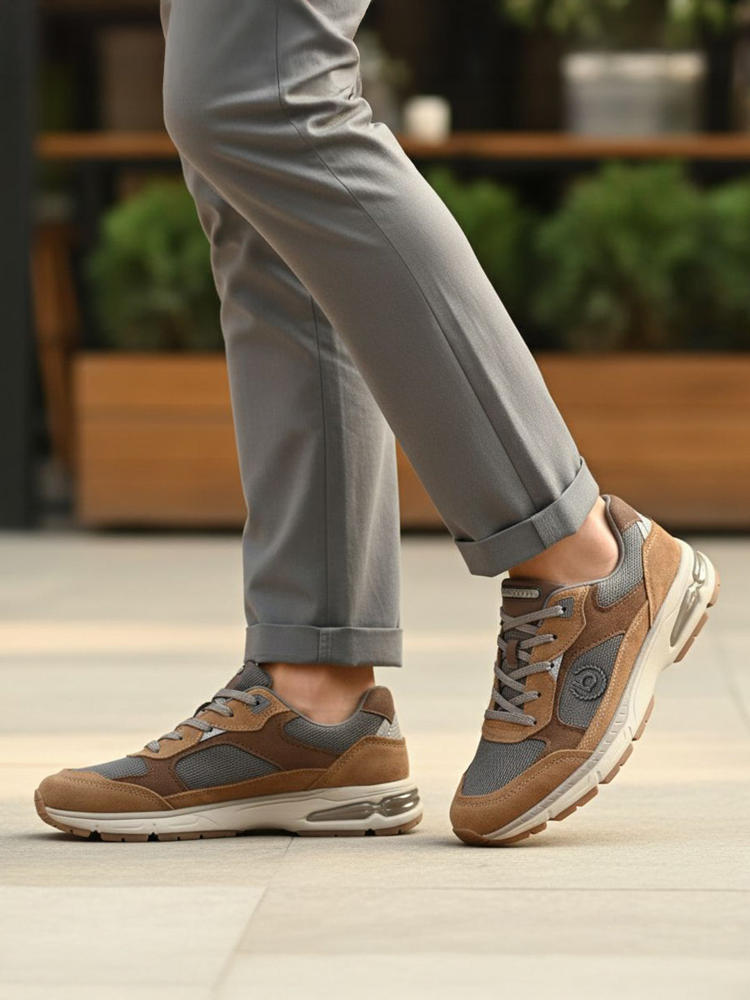 bugatti Parry cognac leather athleisure sneakers with gray mesh detail, worn with gray pants.