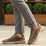 bugatti Parry cognac leather athleisure sneakers with gray mesh detail, worn with gray pants.
