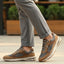 bugatti Parry cognac leather athleisure sneakers with gray mesh detail, worn with gray pants.