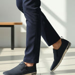 Lifestyle side view of bugatti Glenans dark blue slip-on shoes with zip detail, paired with dress pants.
