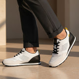 bugatti Sacramento white comfort sneakers with black heel, worn with gray dress pants.
