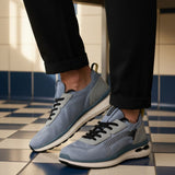 bugatti Sandar blue athleisure sneakers with black laces and white soles, paired with black cuffed pants.

