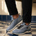 bugatti Sandar blue athleisure sneakers with black laces and white soles, paired with black cuffed pants.
