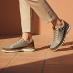 Lifestyle shot of bugatti Rickson beige Comfort Sneakers with zipper detail and brown accents, paired with neutral pants.
