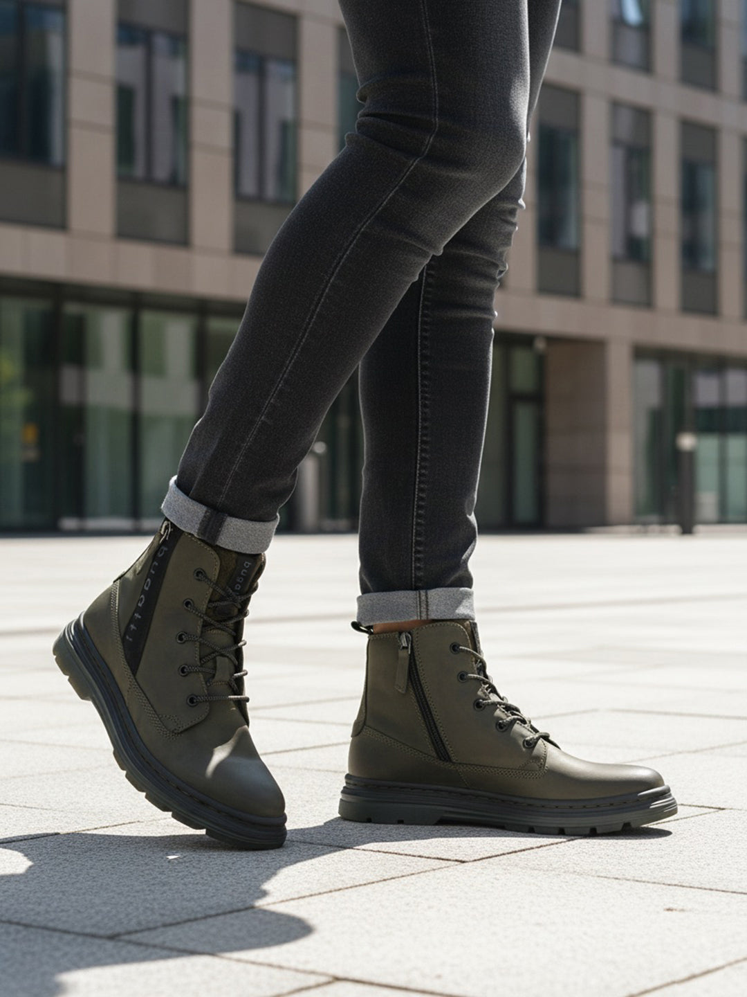 Lifestyle shot of Bugatti Drake boots in dark green leather with laces and side zipper, paired with dark denim jeans.