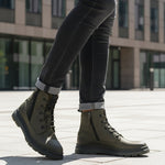 Lifestyle shot of Bugatti Drake boots in dark green leather with laces and side zipper, paired with dark denim jeans.