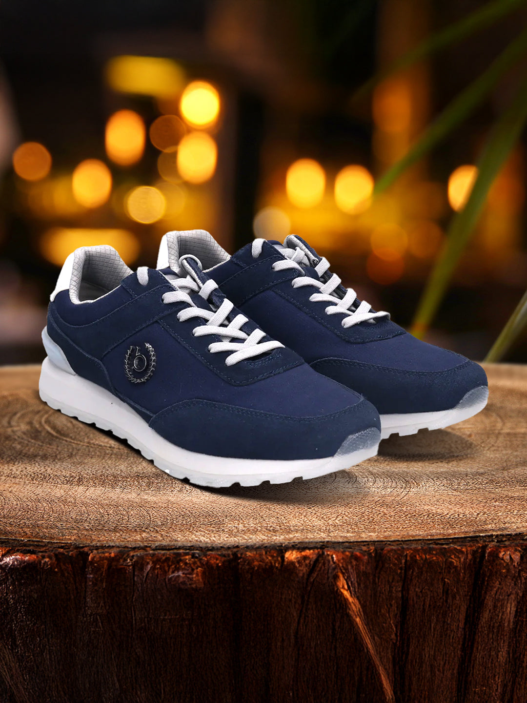 bugatti Atus dark blue sneakers with white laces and soles on a wooden surface with a blurred background.
