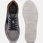 Grey low top sneakers by bugatti featuring navy laces and striped accent, next to the shoe's textured white sole.