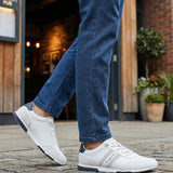 Lifestyle shot of white Bugatti sneakers with striped detail worn with blue jeans.