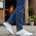 Lifestyle shot of white Bugatti sneakers with striped detail worn with blue jeans.