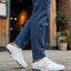 Lifestyle shot of white Bugatti sneakers with striped detail worn with blue jeans.