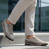 Lifestyle shot of bugatti Trevor beige comfort sneakers, with a zipper, worn with beige pants on steps.

