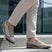 Lifestyle shot of bugatti Trevor beige comfort sneakers, with a zipper, worn with beige pants on steps.
