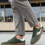 Lifestyle shot of bugatti Carmelo dark green Comfort Sneakers with a white stripe and brown sole.
