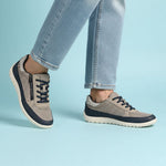 Lifestyle shot of bugatti Bermudas taupe comfort sneakers, with blue trim and dark blue laces, worn with jeans.