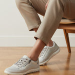 Lifestyle image of bugatti white sneakers, shown with a mesh texture, zipper accent, and worn with casual trousers.