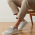 Lifestyle image of bugatti white sneakers, shown with a mesh texture, zipper accent, and worn with casual trousers.