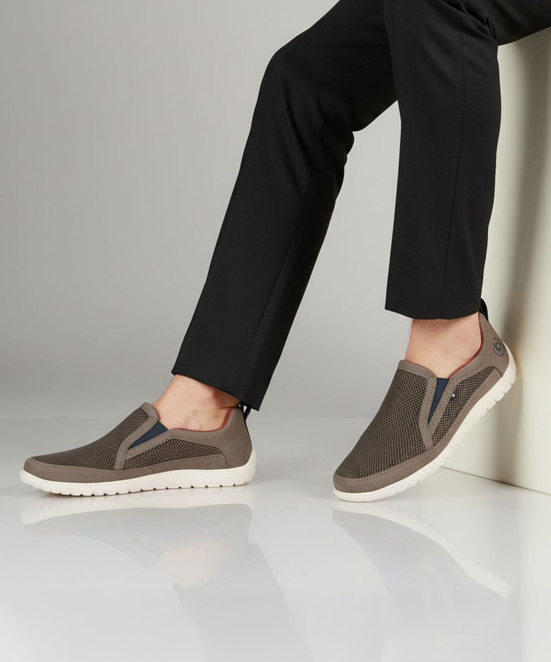 Lifestyle shot of bugatti Bermudas dark gray casual slip-on shoes with a breathable mesh upper and white sole.
