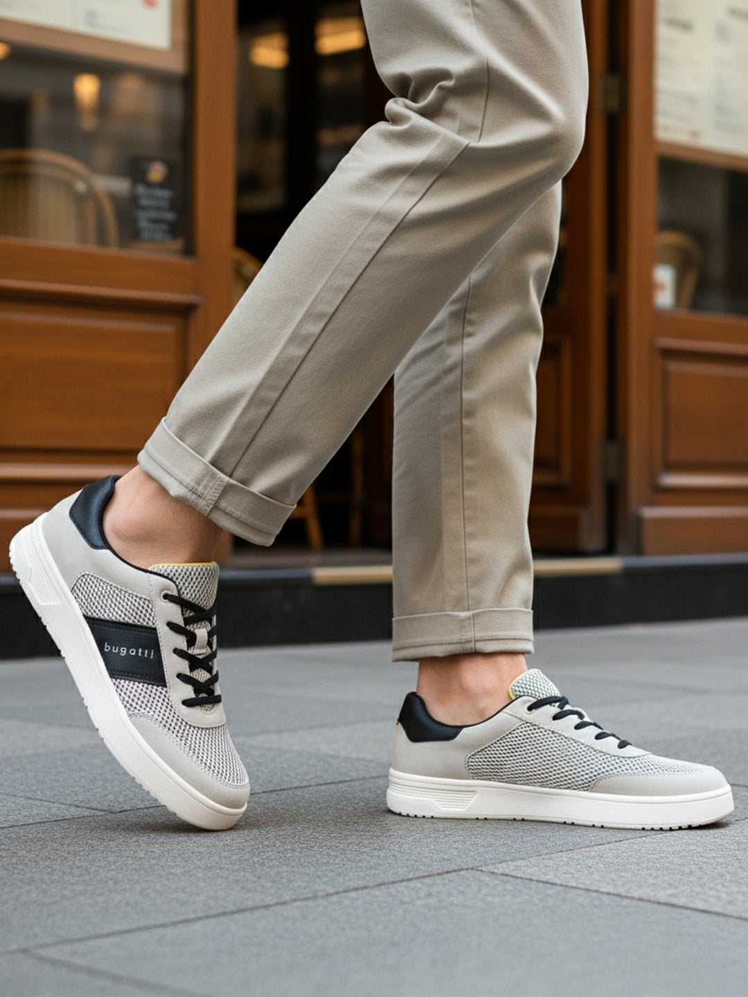 Lifestyle shot of bugatti Mackay light grey comfort sneakers with a black accent and white sole.
