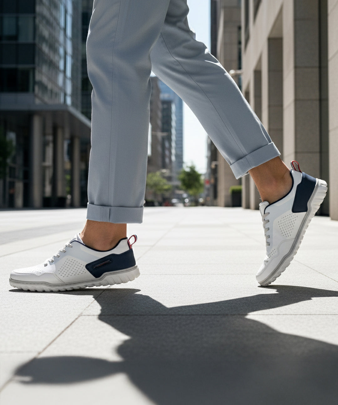 Lifestyle shot of bugatti Samana white leather sneakers with navy and red accents, worn with gray trousers.