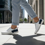 Lifestyle shot of bugatti Samana white leather sneakers with navy and red accents, worn with gray trousers.