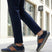 Lifestyle shot of a person wearing navy trousers and bugatti Canario Grey sneakers with brown leather accents.