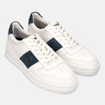 Off-white leather sneakers by bugatti with a navy stripe, white laces, and perforated toe.