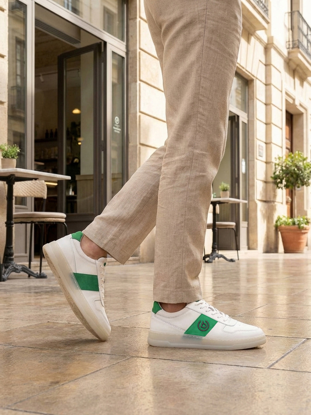 Lifestyle shot of bugatti Franc White premium leather sneakers, featuring a green stripe, worn with khaki trousers.
