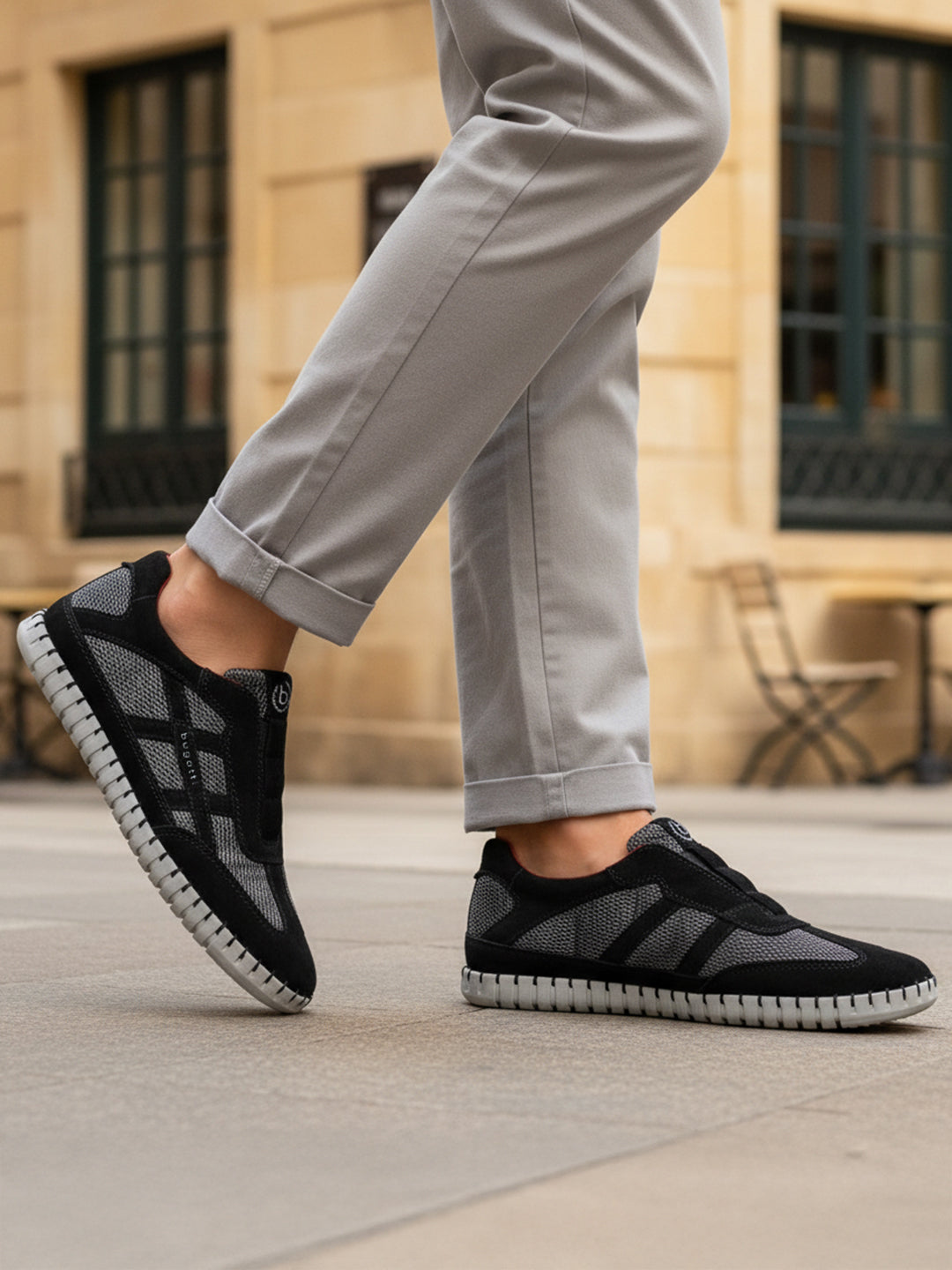 Lifestyle view of bugatti Baloo black leather sneakers with gray mesh detail and a chunky sole.
