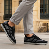 Lifestyle view of bugatti Baloo black leather sneakers with gray mesh detail and a chunky sole.

