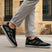 Lifestyle view of bugatti Baloo black leather sneakers with gray mesh detail and a chunky sole.
