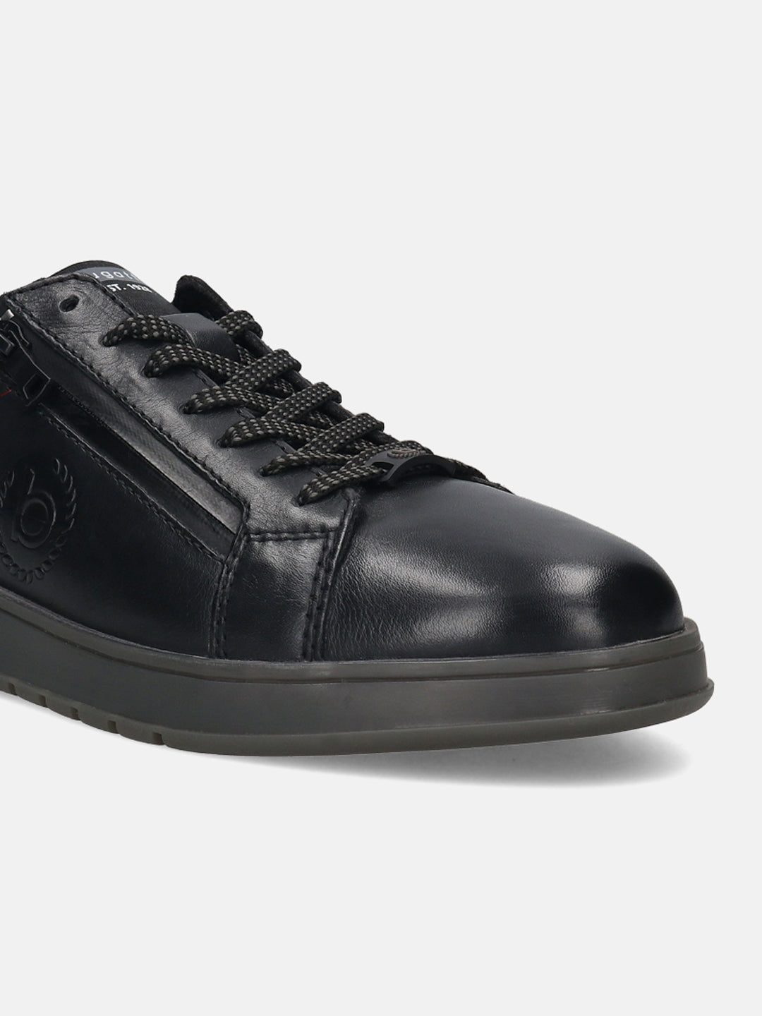 Black leather comfort sneakers by bugatti with a tonal sole and patterned laces, shown in a close up view.