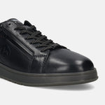 Black leather comfort sneakers by bugatti with a tonal sole and patterned laces, shown in a close up view.