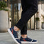 Lifestyle view of bugatti Fiero dark blue comfort sneakers, with white soles and grey laces, worn with dark jeans.

